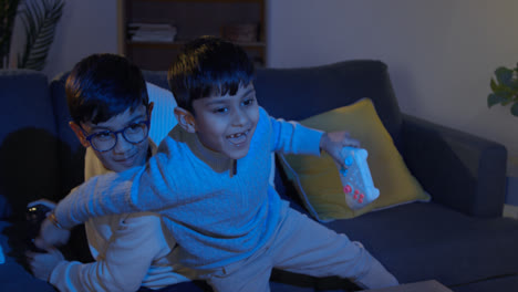 Two-Young-Boys-At-Home-Fighting-Over-Controllers-Playing-On-Computer-Games-Console-On-TV-Late-At-Night-1